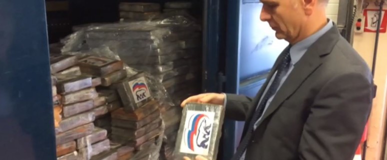 Представитель бельгийской полиции держит в руках брикет с кокаином, маркированный логотипом "Единой России". Кадр из видео бельгийской телерадиокомпании VRT